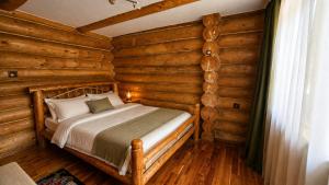 a bedroom with a bed in a log cabin at Cabana Perla Muncelului in Stulpicani