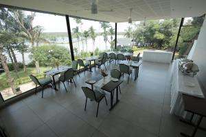 a dining room with tables and chairs and windows at The Brook Serene - A Nature Themed Boutique Resort, Kollam in Kottiyam