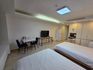 a hotel room with two beds and a table with chairs at Incheon Airport Yeongjong Guesthouse in Incheon