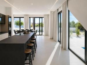 a kitchen with a long bar with stools and windows at Villa Lunga Novalja in Novalja