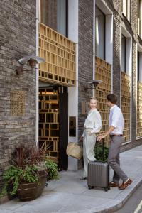 a man and a woman with a suitcase on a sidewalk at The Guardsman Hotel in London