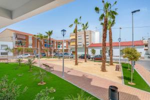 a park with palm trees and benches and buildings at Pinatar Luxury in San Pedro del Pinatar