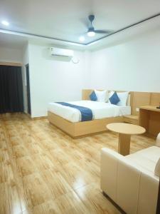 a bedroom with a bed and a couch and a table at Hotel Shiny Grand in Guwahati