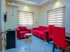 a waiting room with red couches and a table at Amnu Homes Apartment in Ilorin
