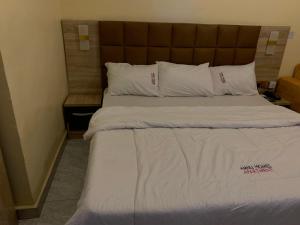 a bed with white sheets and pillows in a room at Amnu Homes Apartment in Ilorin