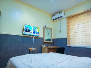 a bedroom with a bed and a flat screen tv at Amnu Homes Apartment in Ilorin