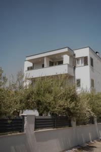 ein weißes Gebäude mit Bäumen davor in der Unterkunft Sobe Vincentius in Metković
