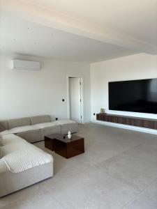 a living room with a couch and a flat screen tv at Penthouse Jacuzzi SeaView Suite in Makarska