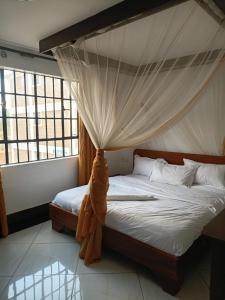 a bedroom with a bed with a mosquito net at The Sychar Palace Hotel in Kanga