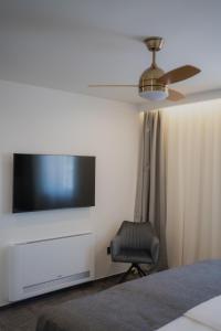 ein Schlafzimmer mit einem Flachbildfernseher und einem Stuhl in der Unterkunft Sobe Vincentius in Metković