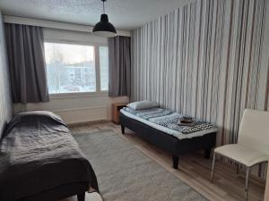 a bedroom with a bed and a chair and a window at Annalassa kahden makuuhuoneen asunto in Tampere