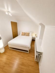 a white bedroom with a bed and a staircase at Simple studio near Kirchberg in Luxembourg
