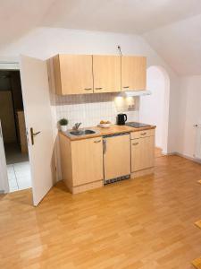 a kitchen with wooden cabinets and a wooden floor at Simple studio near Kirchberg in Luxembourg