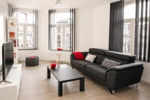 a living room with a black couch and a table at Les Suites de Nanesse in Liège