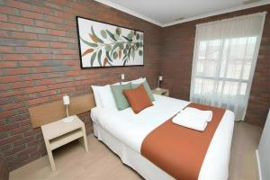 a bedroom with a large bed and a brick wall at Jacaranda Apartments in Swan Hill +6 photos
