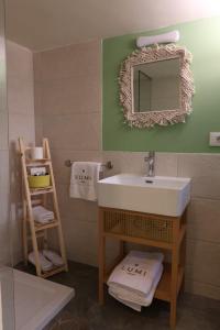 a bathroom with a sink and a mirror and towels at LUMI amchit in Al Qarfī