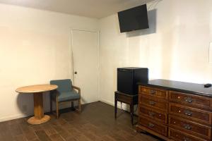 a room with a table and a dresser and a tv at Oak Motel Modesto CA in Modesto