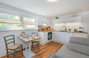 a kitchen with white cabinets and a table and chairs at Krauses Unterdeck in Loddin