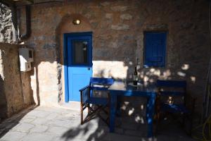 a blue door and a table and chairs in front of a building at Avgonima Sunset Medvial Suite in Chios