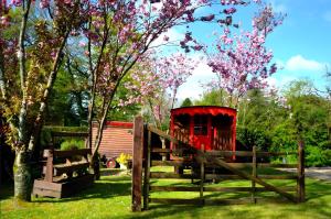 a wooden fence and a tree with pink flowers at Roulotte Champêtre Bella in Brix