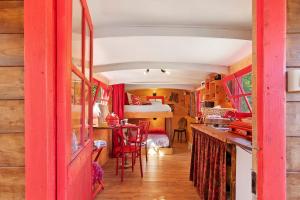 a red room with a table and a bed in a room at Roulotte Champêtre Bella in Brix