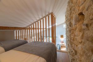 a bedroom with two beds and a stone wall at L'ormeau in Charols