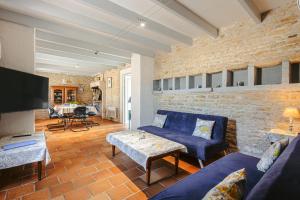 a living room with blue couches and a brick wall at Gite de l'Ocean in Genouillé