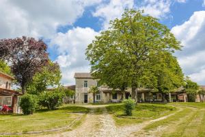 an old farmhouse with a tree and a dirt road at Gite de l'Ocean in Genouillé