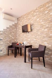 a dining room with a table and chairs and a tv on a brick wall at Malpensa Garden in Case Nuove
