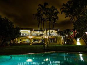 a house at night with a swimming pool in front of it at Driftwood on 10 La Lucia in Durban
