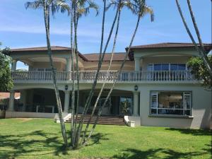 a house with palm trees in front of it at Driftwood on 10 La Lucia in Durban
