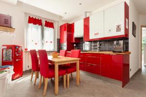 a red kitchen with a wooden table and red chairs at Malpensa Garden in Case Nuove