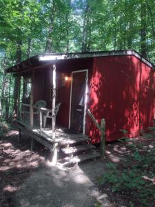 a red cabin in the woods with a porch and a bench at Thunder Ridge Cabins B&B - Wolf Den in Rockbridge