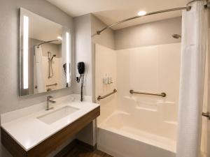 a bathroom with a sink and a bath tub at Microtel Inn & Suites by Wyndham Macon in Wesleyan Hills +25 photos