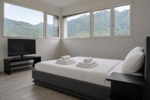 a bedroom with a bed with a television and windows at Villa Sementina - Luxury Stay with Pool and Gym - 15 m to Lake Maggiore in Bellinzona