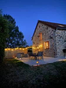 a patio with a table and chairs in front of a building at Gîte des Charbonneaux in Avrée