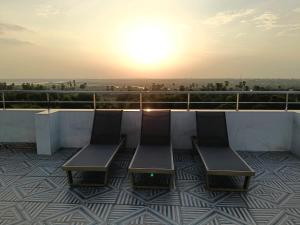 two benches on a balcony with the sunset in the background at Sri Vasavi Regency in Mahabalipuram