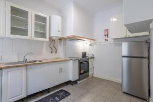 a kitchen with white cabinets and a stainless steel refrigerator at AL Fancy Discoveries in Lisbon +10 photos