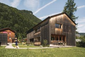 a wooden house with a woman walking past it at Ferienhaus Islen in Mellau