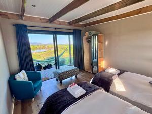 a room with two beds and a chair and a window at Libertas Guest Farm in Hoekwil