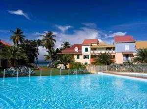 a large swimming pool in front of a house at coconut beach citerne marisol in Le Gosier