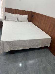 a bed with white sheets and a wooden headboard at Highway 20 Homestay in Phong Nha