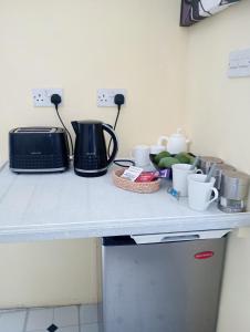 a kitchen counter with a toaster a toaster and some cups at Kaye Daisy in Vieux Fort