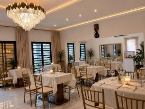 a banquet hall with white tables and chairs and a chandelier at Maria Gracia House in Grand-Bassam