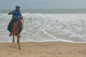 a man riding a horse on the beach at Isimi haven in Lekki