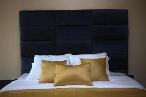 a bed with a blue headboard with four pillows at Isimi haven in Lekki +1 photo