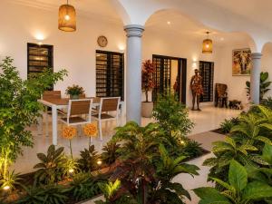 a woman is standing in a room with plants at Maria Gracia House in Grand-Bassam