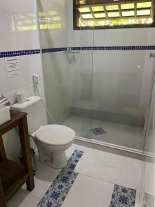 a bathroom with a toilet and a glass shower at Pousada Recanto Afetivo in Trindade