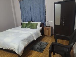 a bedroom with a large bed with green pillows at Aama Ghar Siliguri in Siliguri