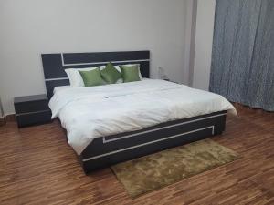 a bedroom with a large bed with green pillows at Aama Ghar Siliguri in Siliguri